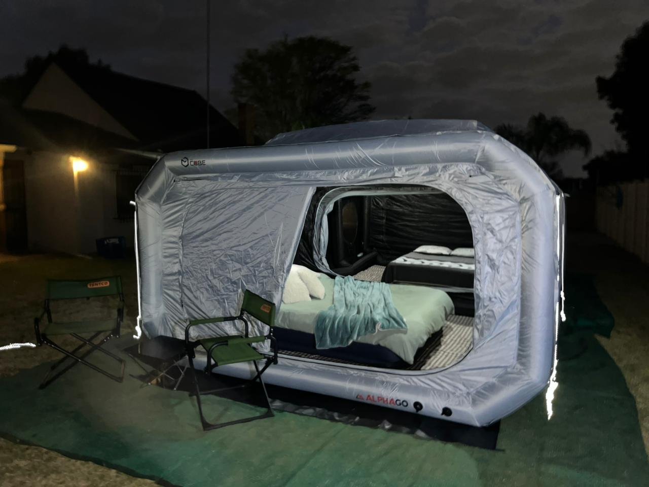 The Wander Cube Starlight inflatable tent lit up at night in Pretoria with LED rope lighting outlining the doorway and a made-up bed inside