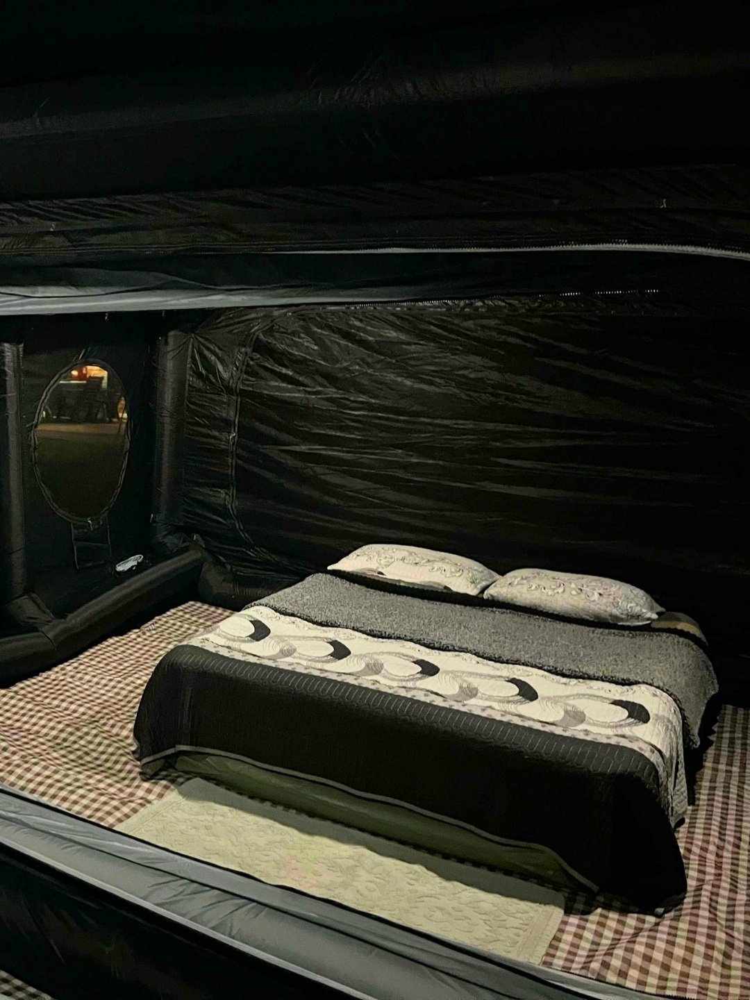 Inside the blacked-out Wander Cube Starlight with a second bed made up and an oval window in the far wall