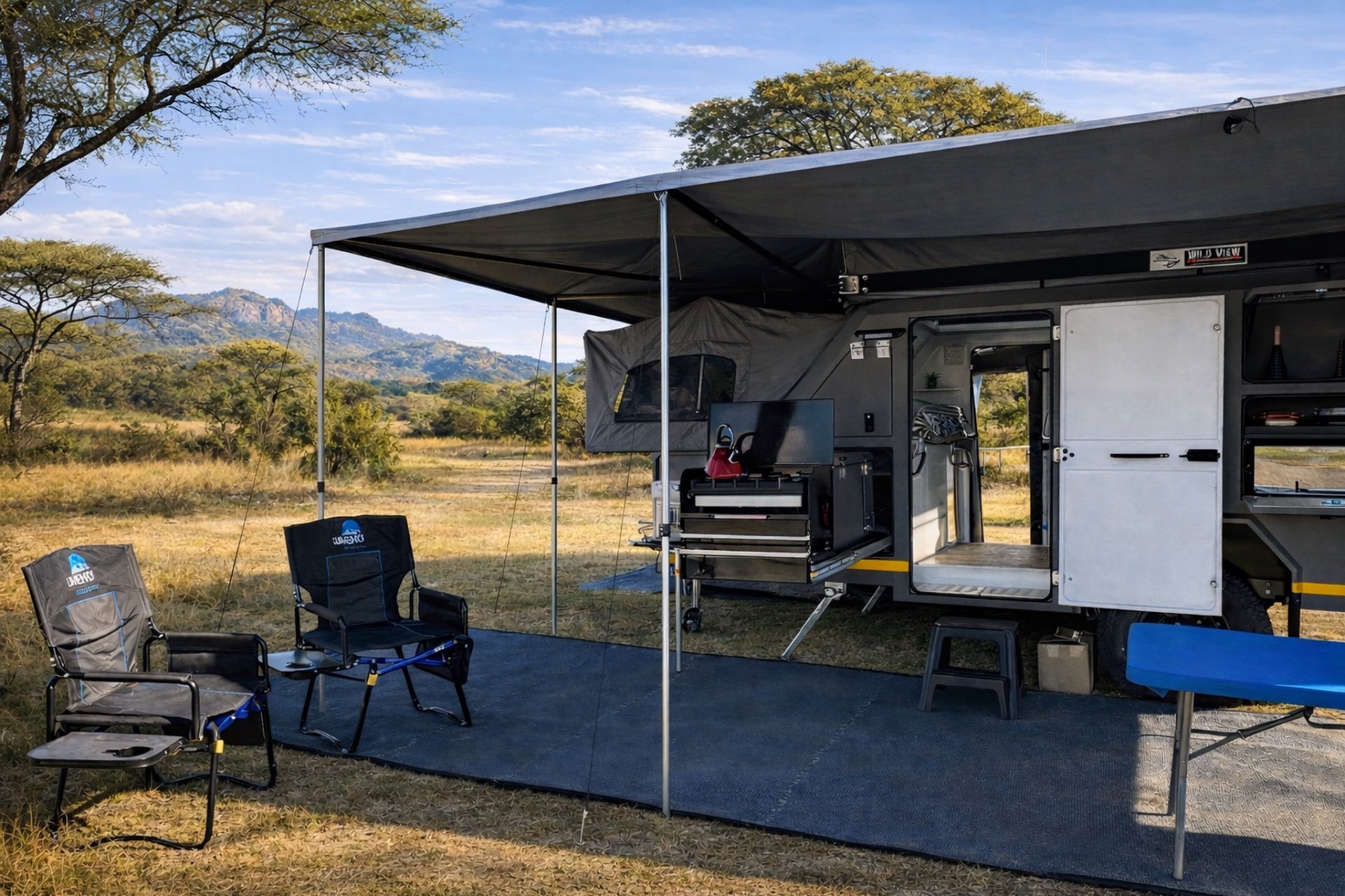 Off-road caravan with an awning, two camp chairs and a slide-out kitchen set up in the bushveld