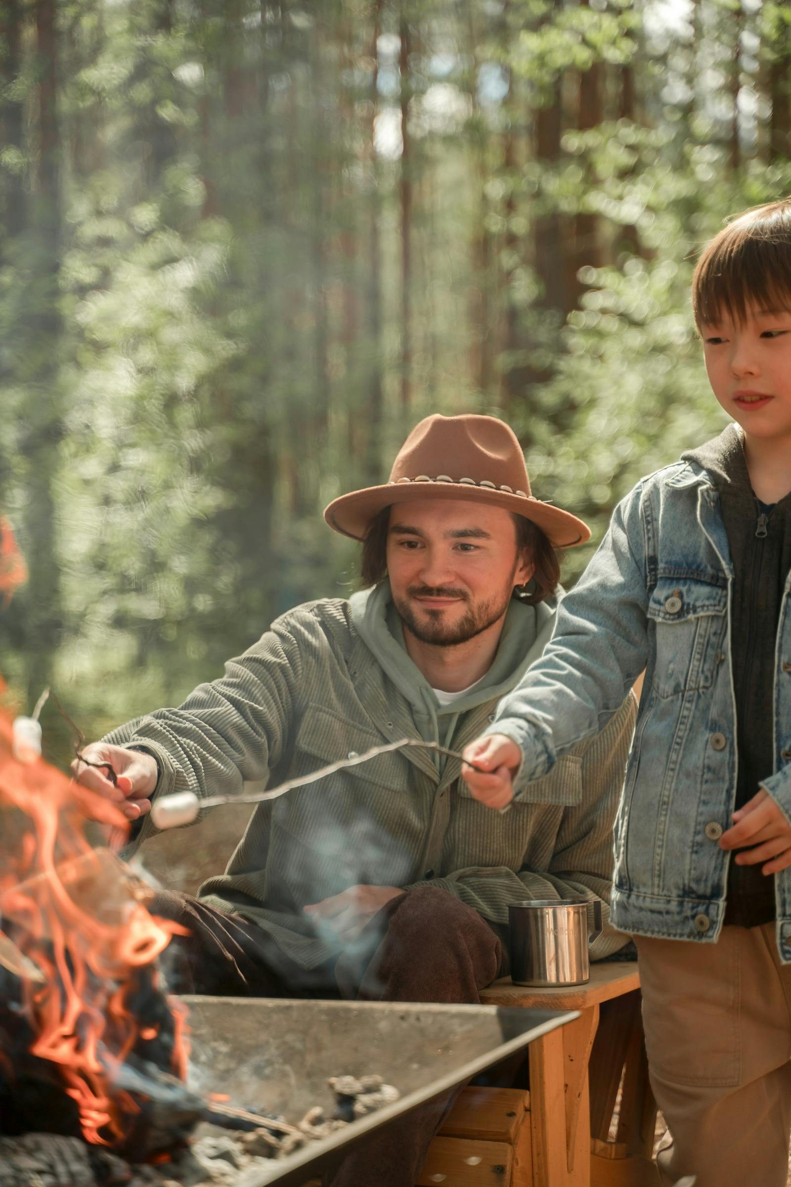 Father and son roasting marshmallows over a campfire while camping together on a father-son weekend
