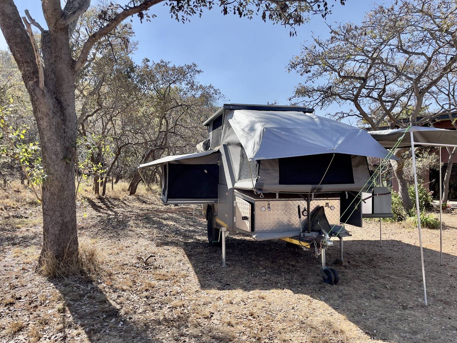 Off-road caravan with rooftop tent opened up under mopane trees in dry winter bushveld
