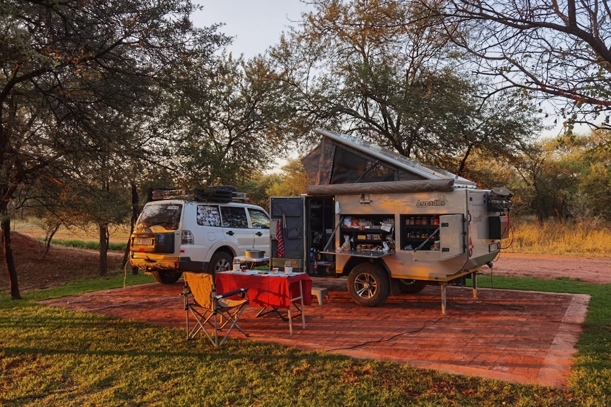 Camping setup with off-road caravan trailer at Plaas Toe in the Dinokeng bushveld at sunset